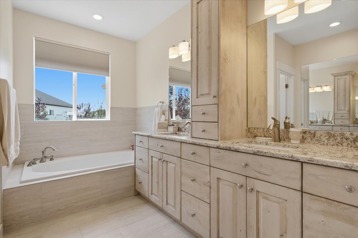 Dual vanity with granite countertops, light wood-finish cabinetry, and undermount sinks