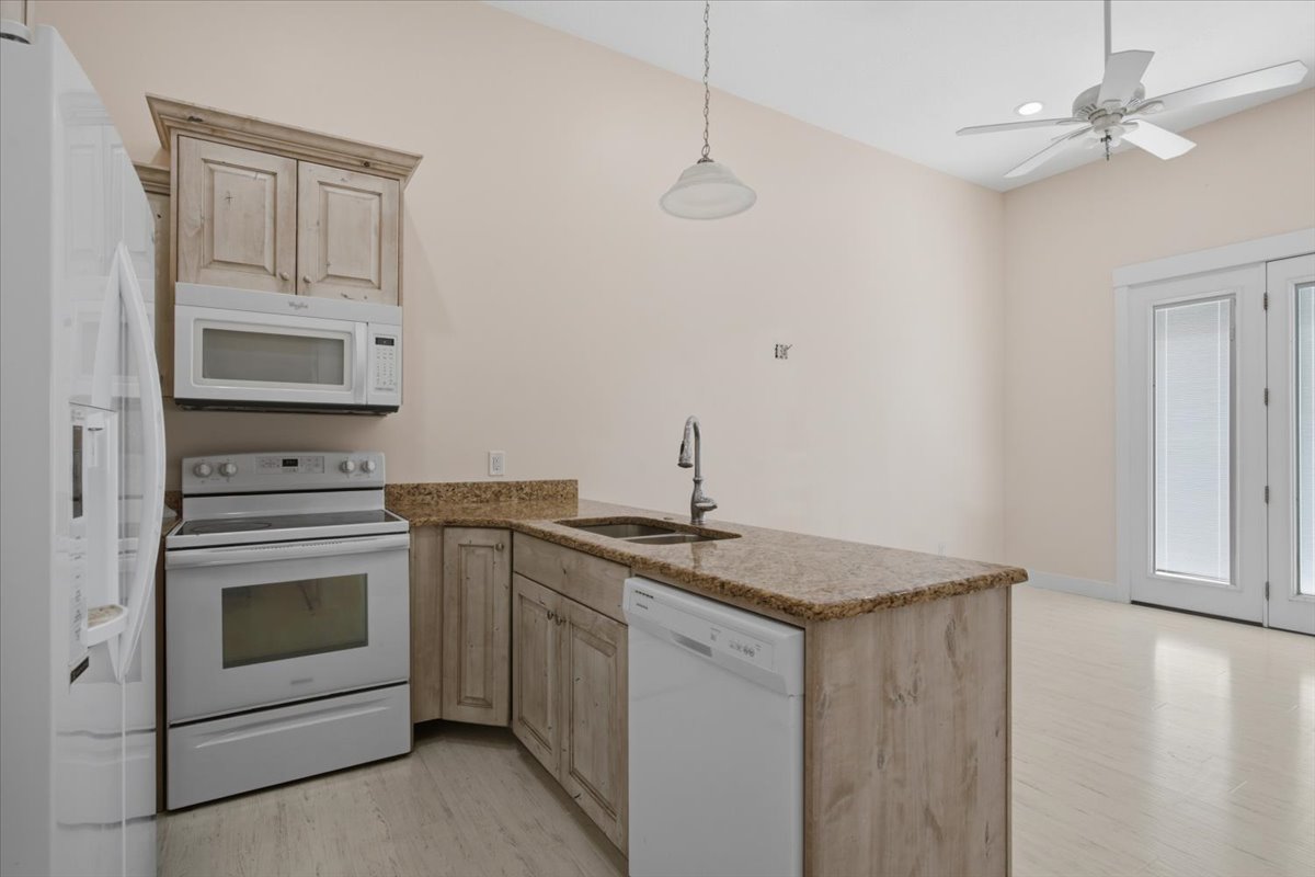 Kitchen featuring light wood-finish cabinetry, speckled countertops, and an integrated kitchen island with sink