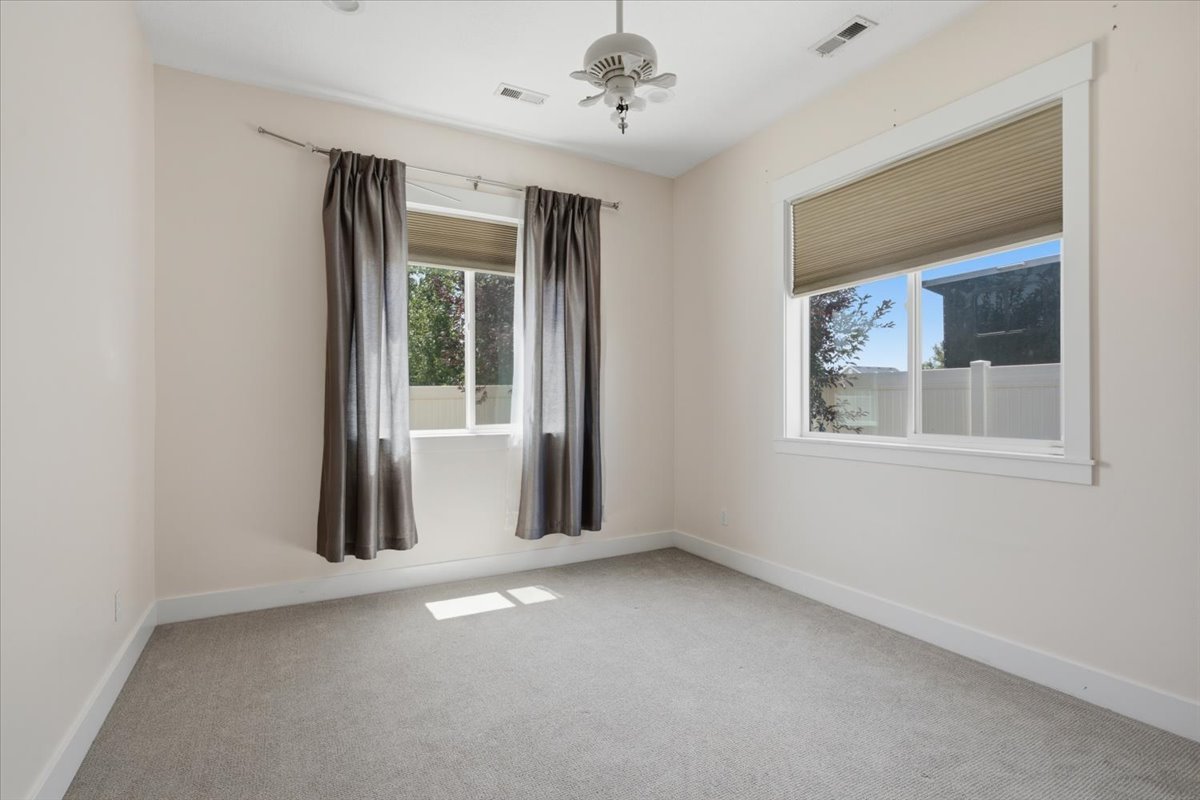 Carpeted interior space featuring two windows with white trim, a ceiling fan, and recessed lighting