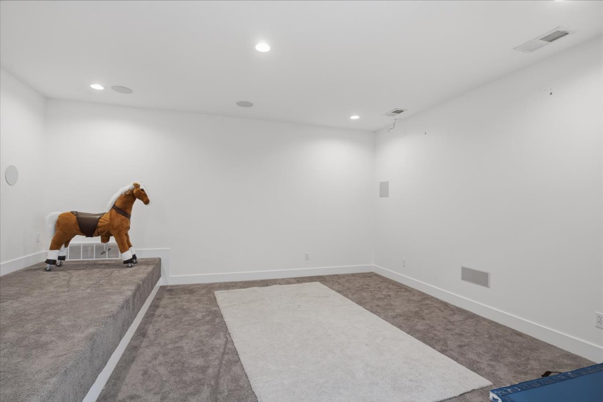 Spacious room with white walls, recessed lighting, and carpeted flooring