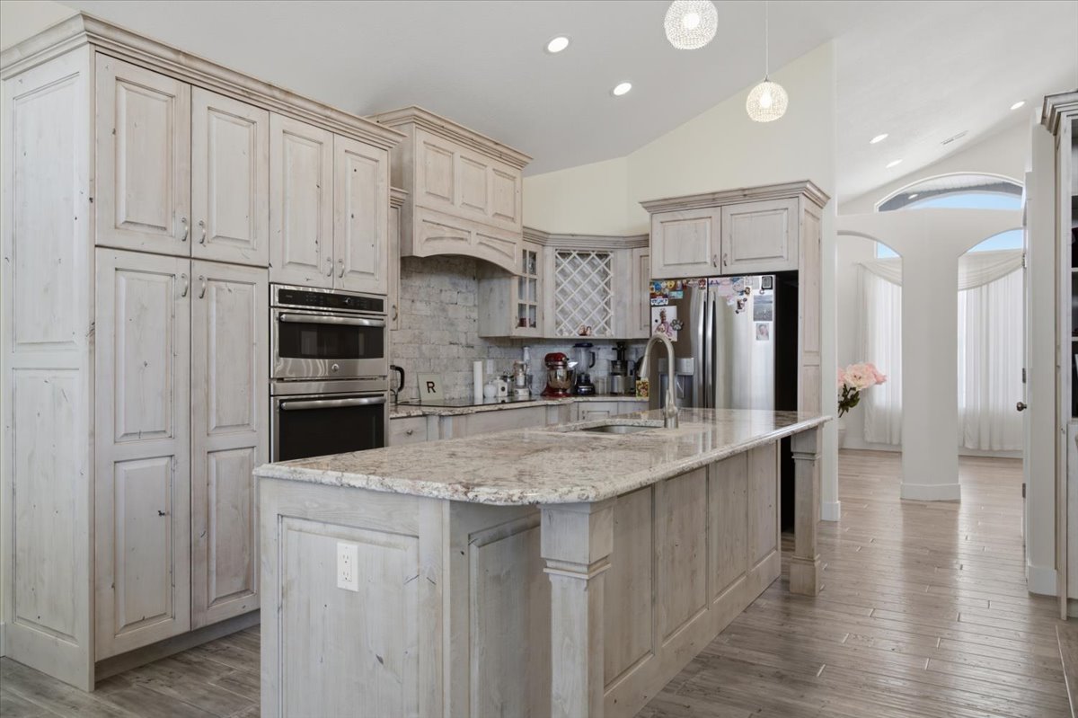 Kitchen featuring extensive light-toned cabinetry, stainless steel double ovens, and a central island with a stone countertop