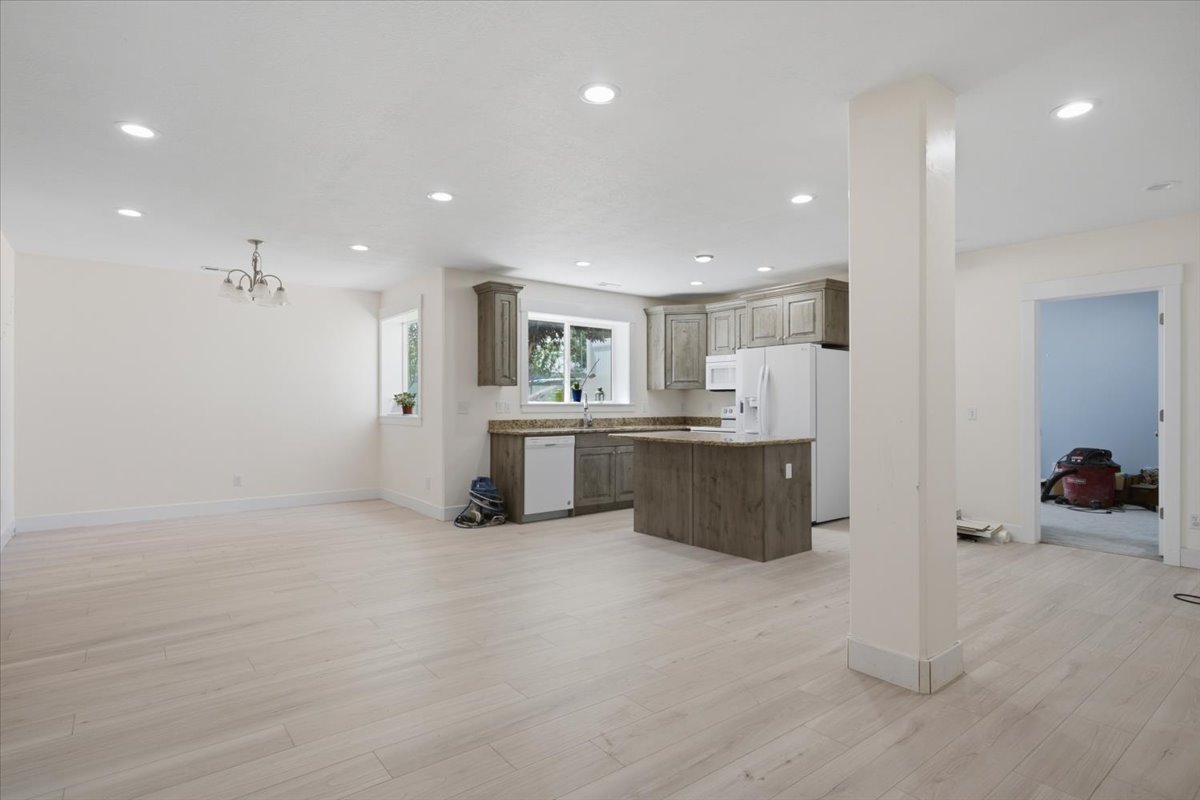 Open-concept living space featuring light wood-finish flooring, recessed lighting, and a kitchen with wood cabinetry and a central island