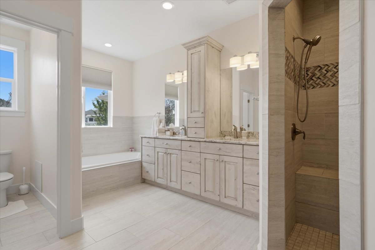 Bright bathroom featuring a dual vanity with light cabinetry and stone countertops