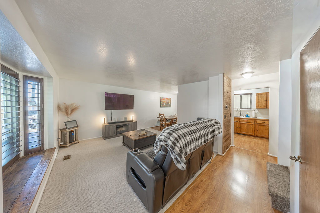Spacious living area featuring light-toned carpeting and wood-finish flooring