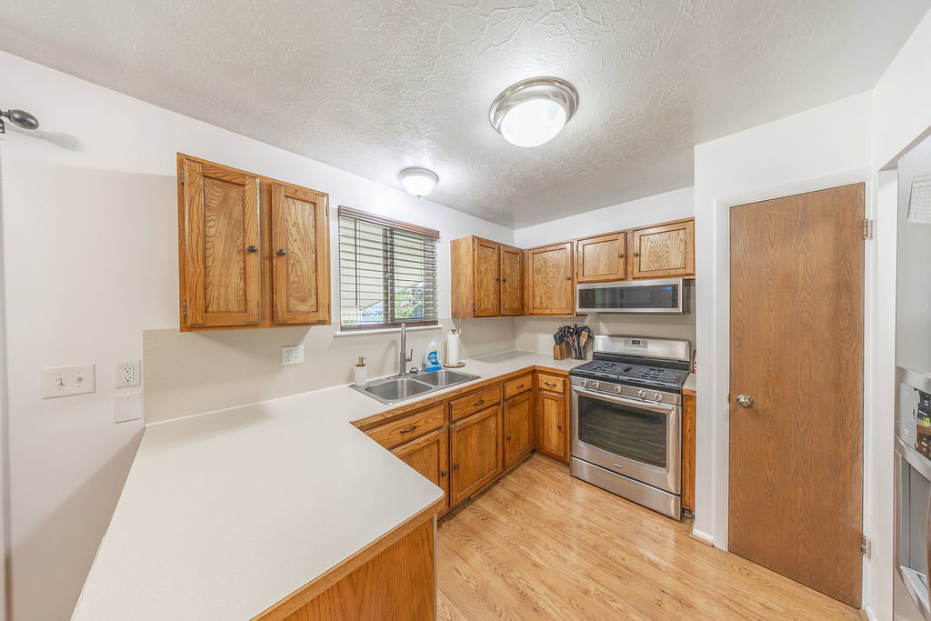 Kitchen featuring wood-finish cabinetry, light-toned countertops, and wood-finish flooring