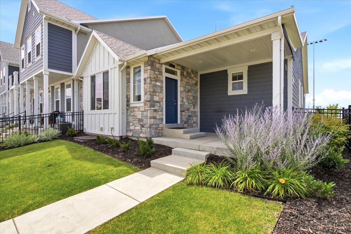 Contemporary exterior featuring stone accents, blue siding, white trim, a covered porch, and a concrete pathway