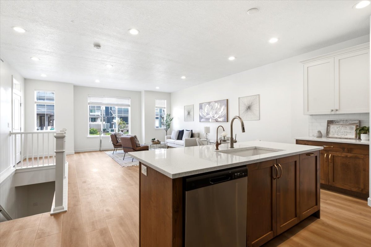 Open-concept living space featuring a central island with a stainless steel dishwasher and a single-basin sink
