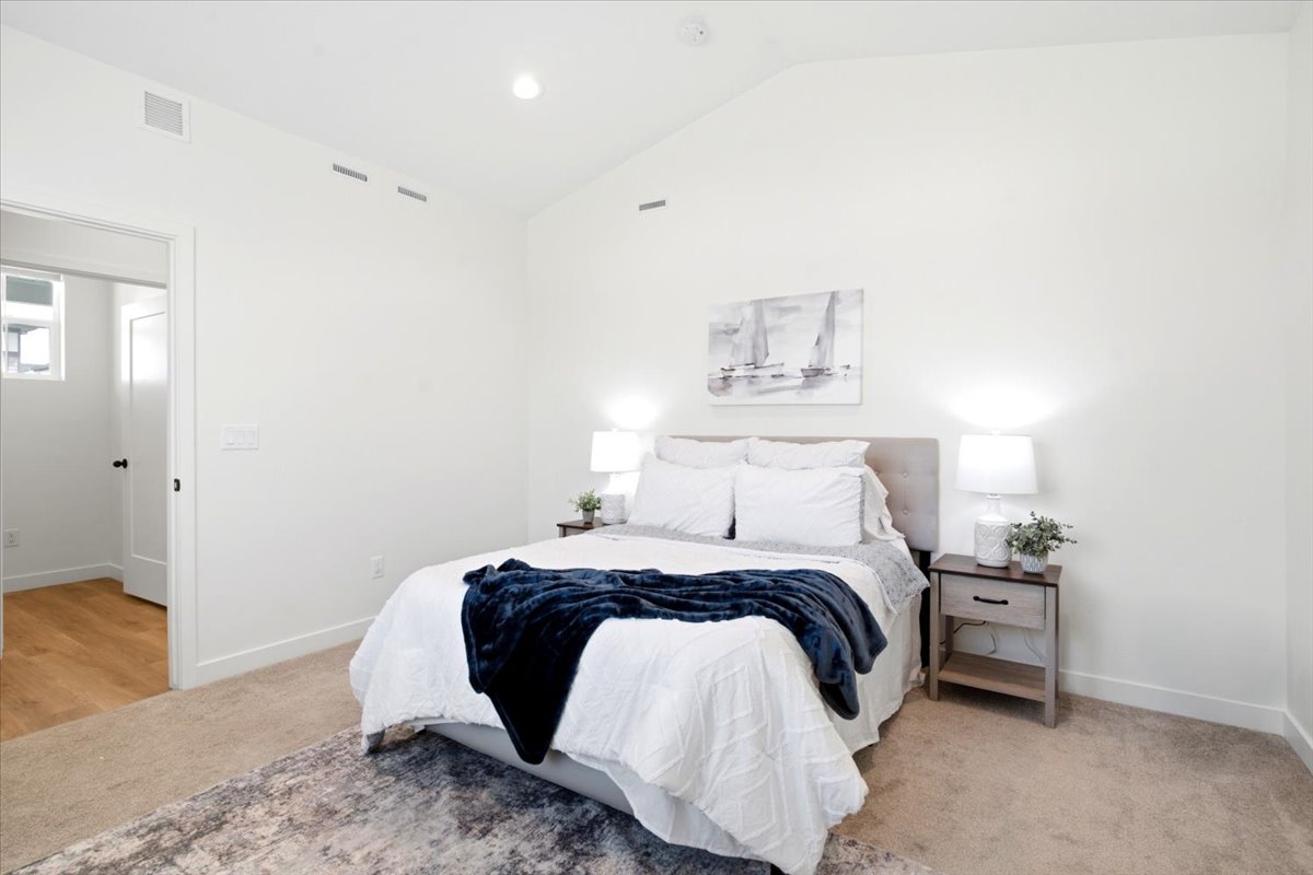 Vaulted ceiling bedroom with neutral wall tones and recessed lighting