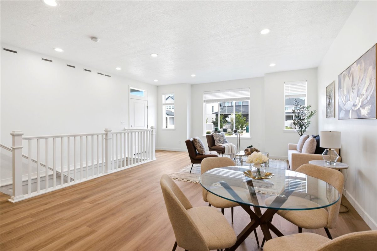 Open-concept living area with wood-finish flooring, recessed lighting, and white baluster railing
