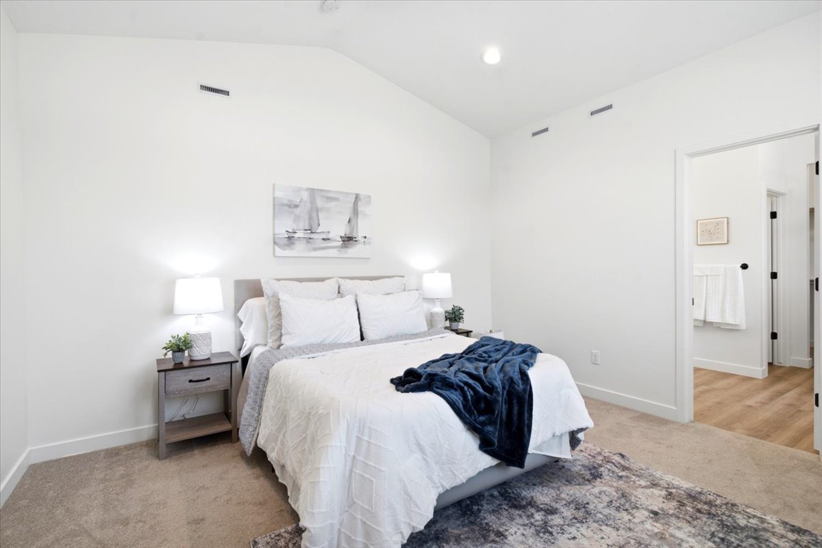 Vaulted ceiling bedroom featuring plush carpet flooring, recessed lighting, and a neutral wall color palette