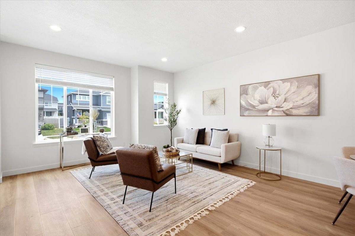 Spacious living area featuring light wood-finish flooring, recessed lighting, and large windows