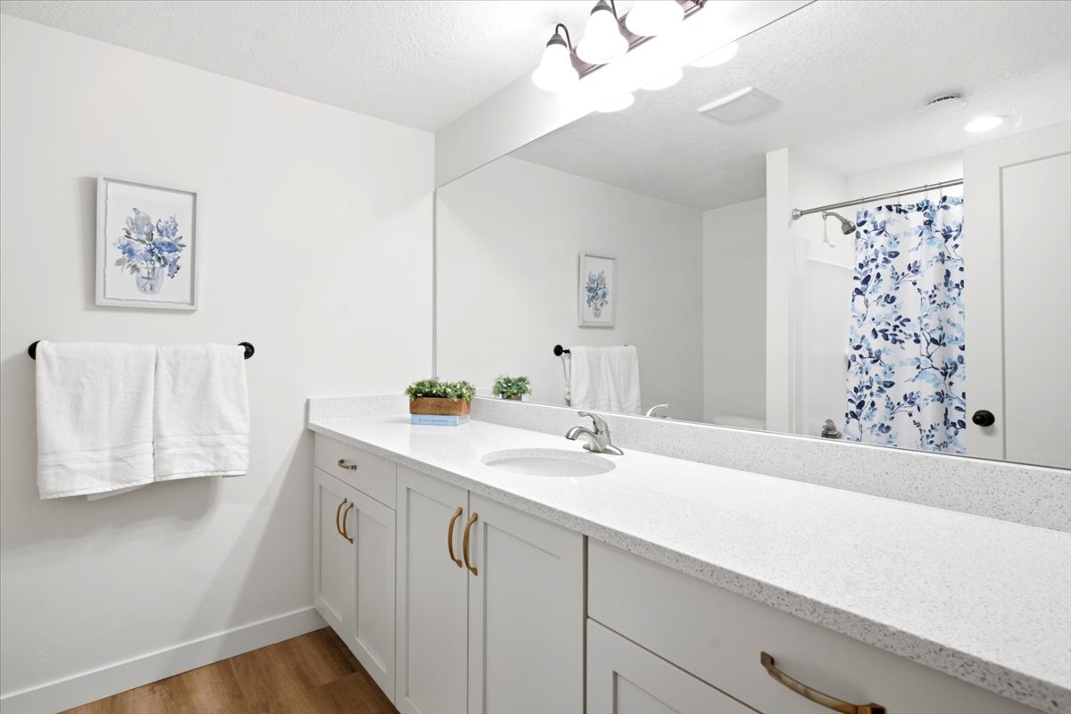 Bathroom featuring a white vanity with multiple cabinet doors and drawers, a white countertop, an integrated sink, and a large wall-mounted mirror