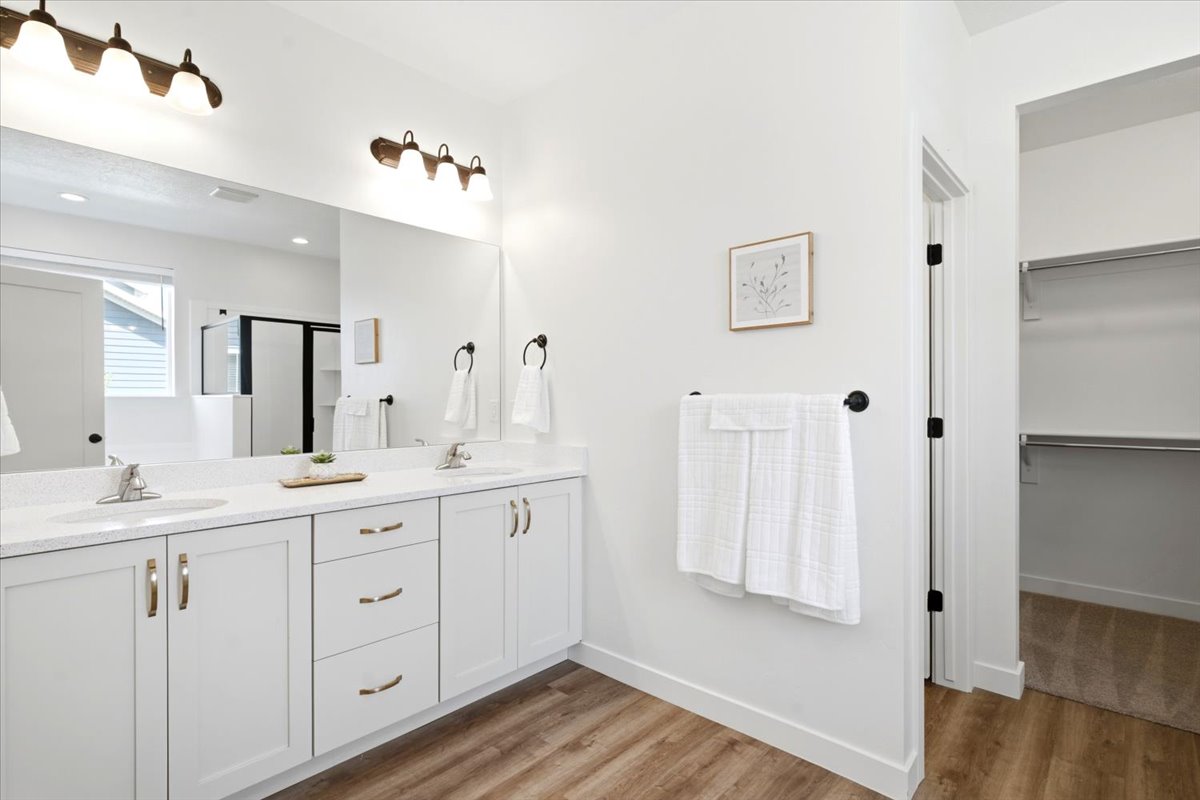 Dual vanity featuring white cabinetry, gold-finish hardware, and a light-toned countertop