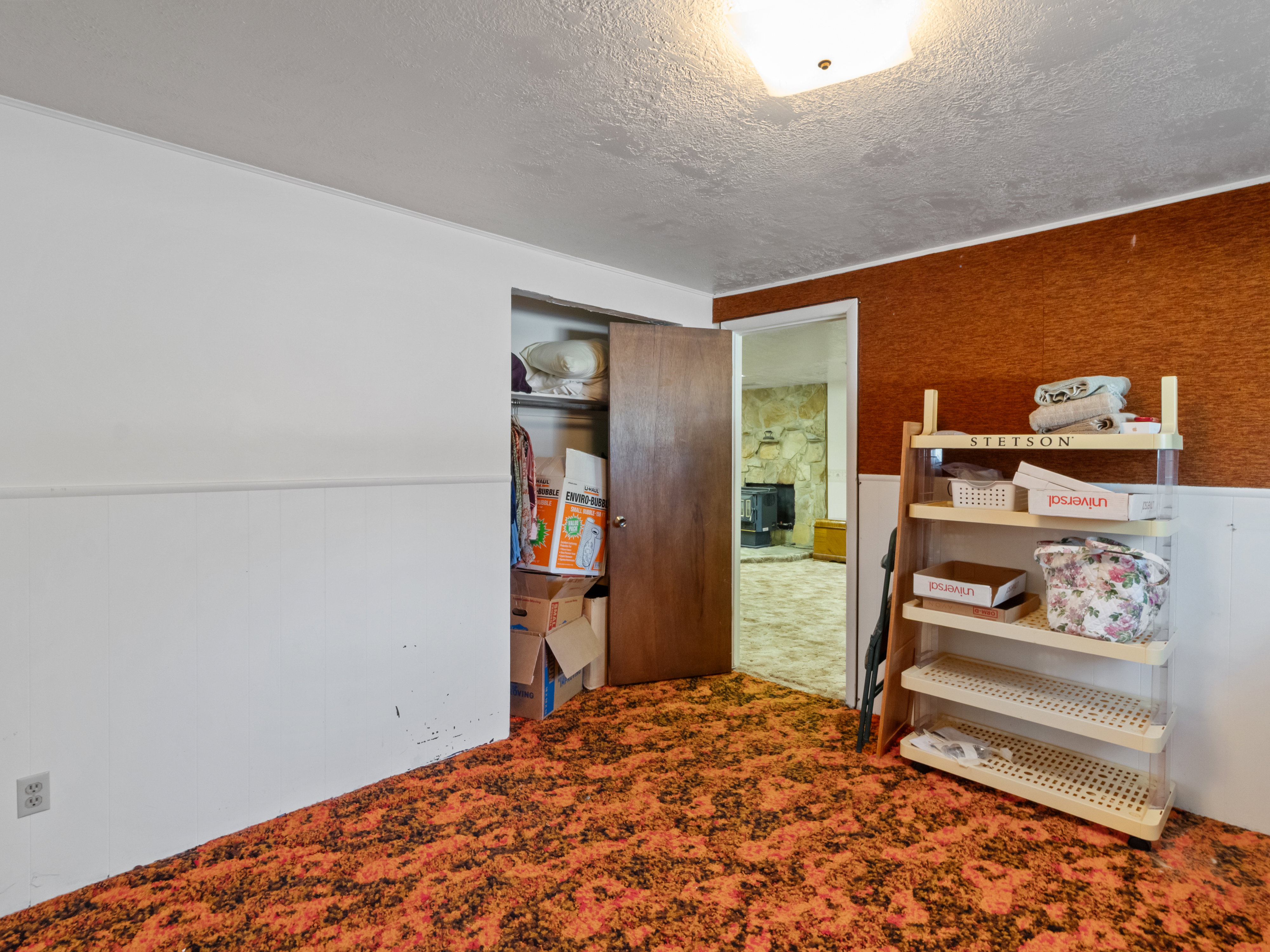 Room featuring distinct orange-patterned carpeting and white wainscoting