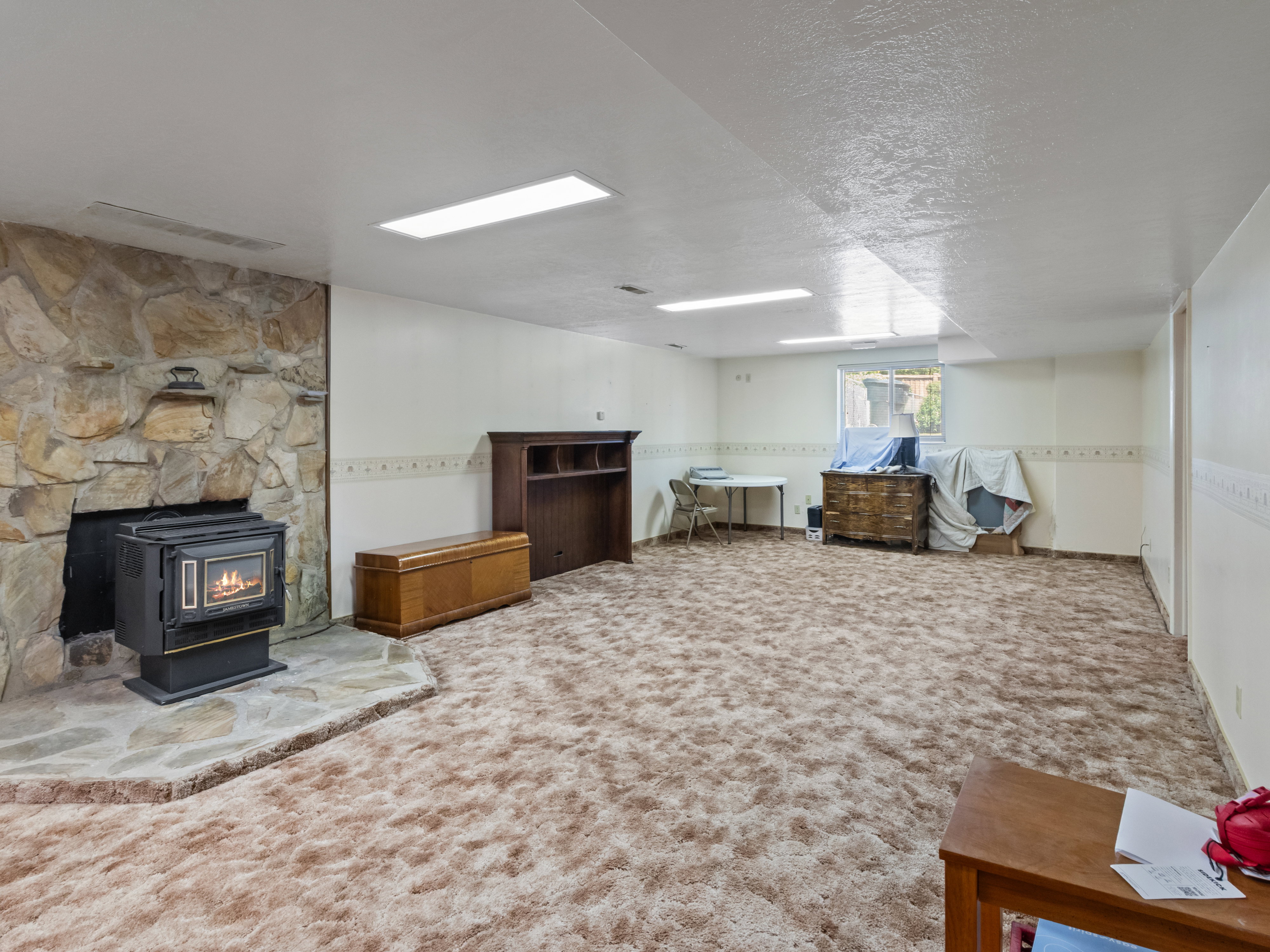 Spacious finished room featuring a stone-clad fireplace with an insert, plush carpeting, and recessed lighting