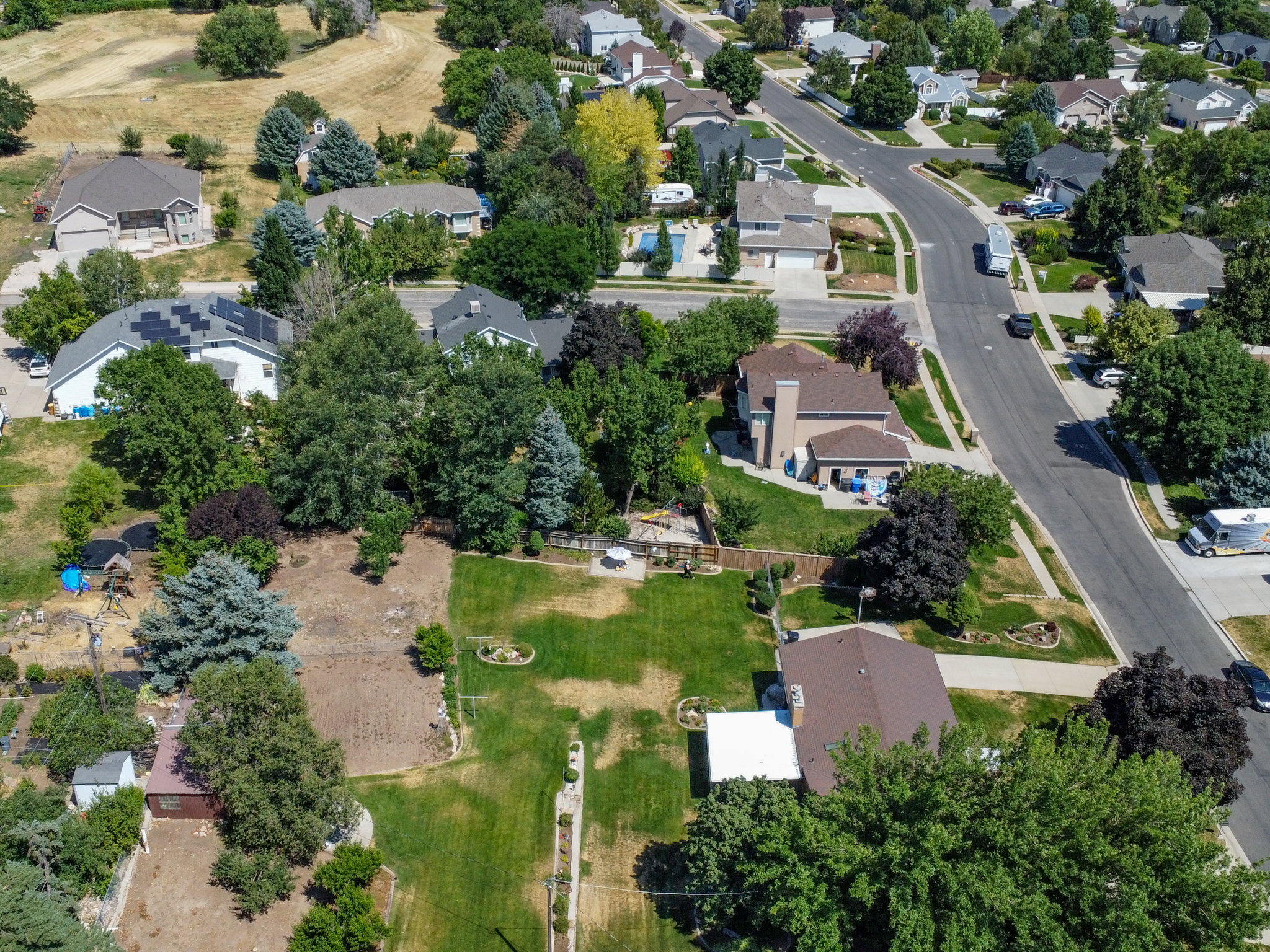 Expansive property featuring a large undeveloped lot, mature trees, and existing landscaping