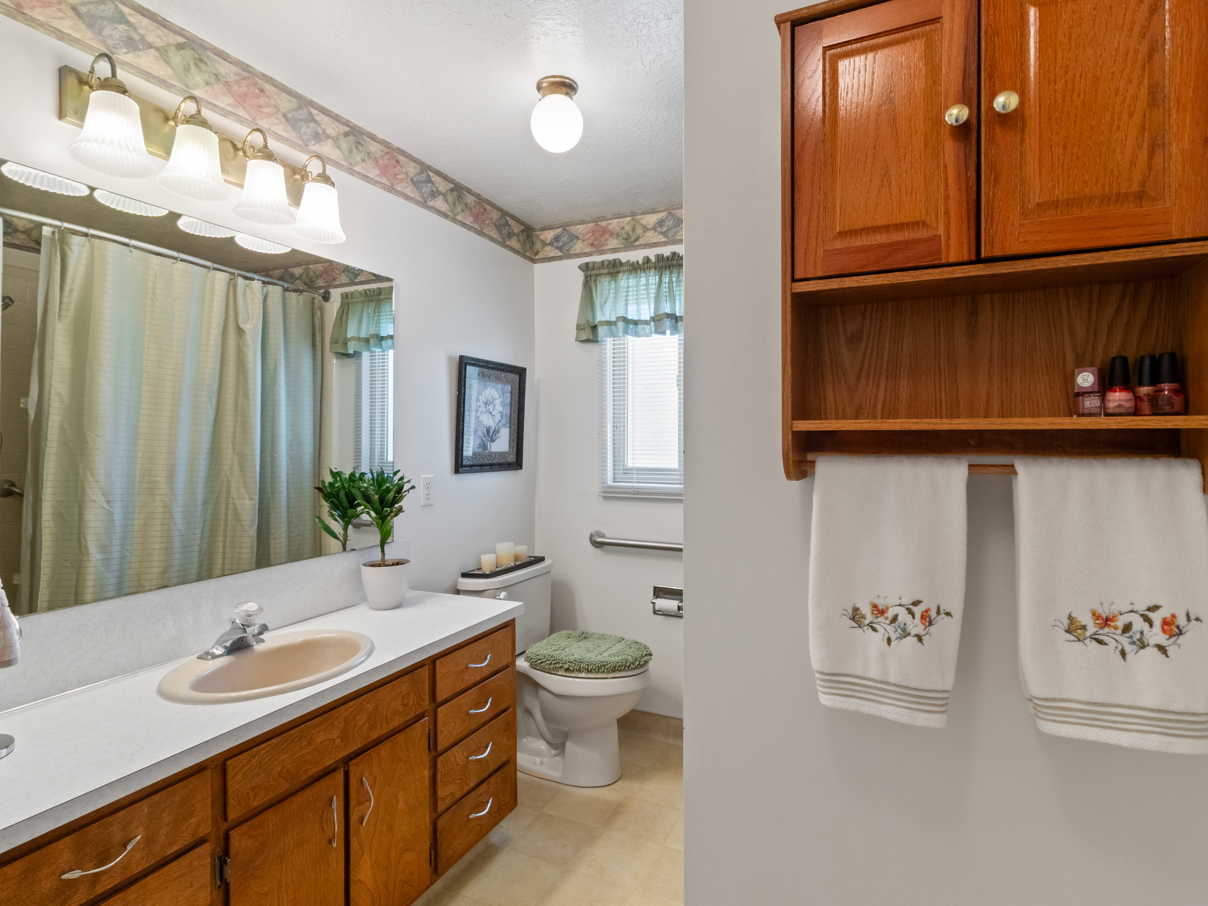 Bathroom featuring a vanity with an integrated sink and wood-finish cabinetry, a large mirror, and a wall-mounted light fixture