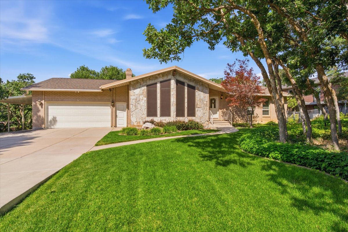 Ranch-style residence featuring stone and brick exterior, a two-car garage, and an attached carport
