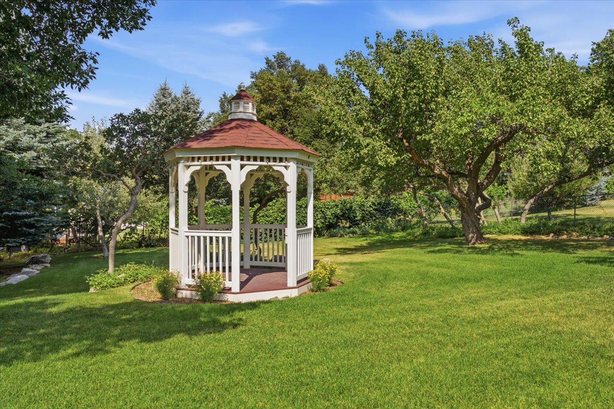 White wooden gazebo with a red shingled roof