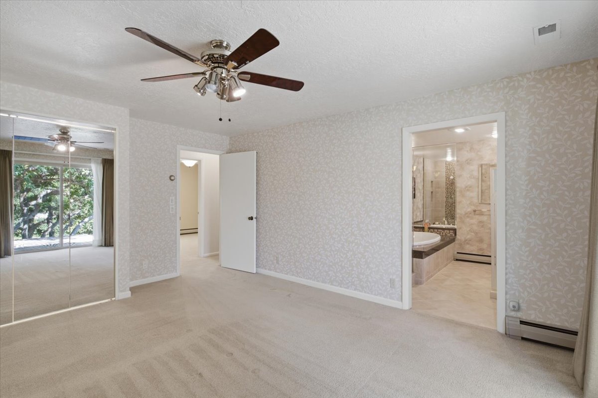 Bedroom featuring wall-to-wall carpeting, patterned wallpaper, and a ceiling fan with integrated lighting