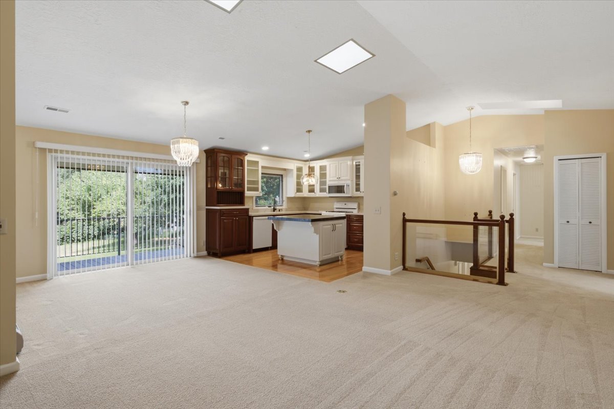 Open-concept living area with neutral carpeting, recessed lighting, and a skylight