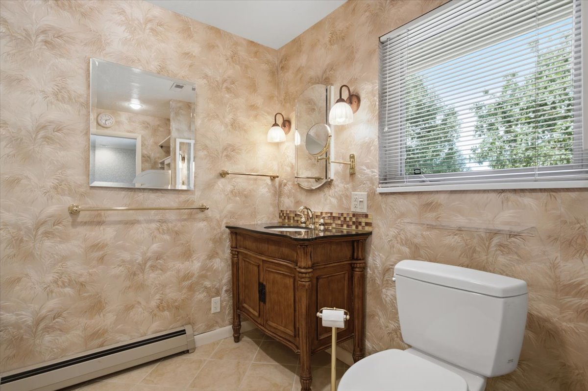 Bathroom featuring a vanity with a dark wood cabinet, a mosaic tile backsplash, and a polished countertop