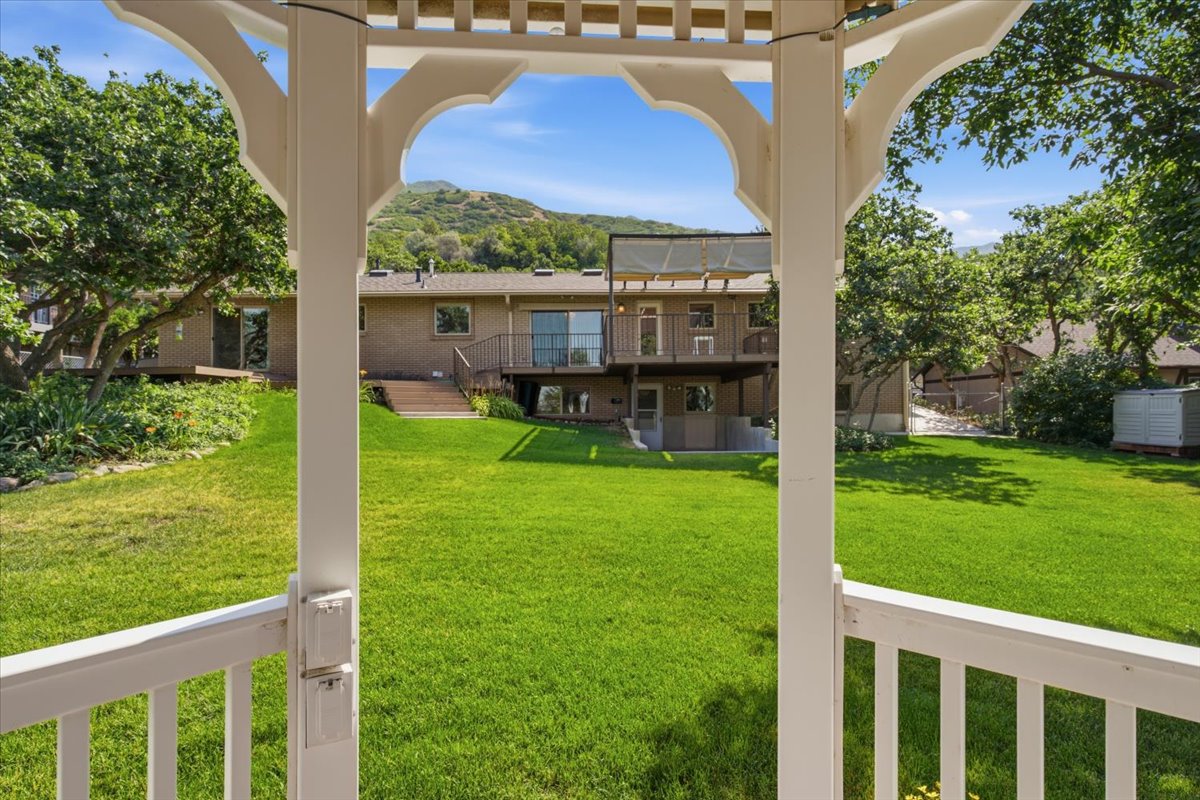 Expansive backyard featuring a manicured lawn, mature trees, and mountainous terrain in the background