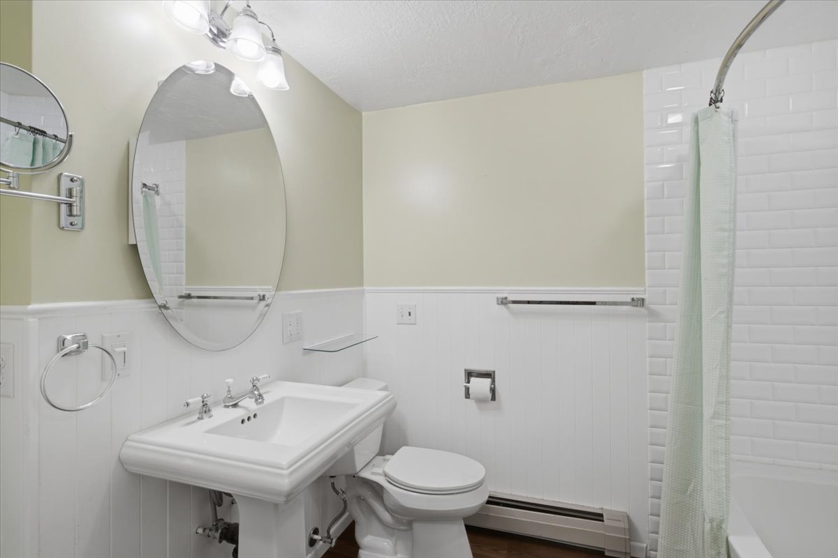 Bathroom featuring a white pedestal sink with chrome fixtures, an oval mirror, and a three-light vanity fixture