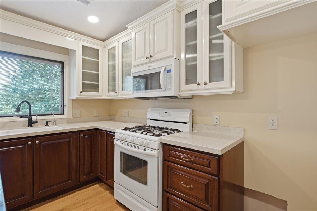 Kitchen featuring two-tone cabinetry with white upper cabinets and dark wood-finish lower cabinets