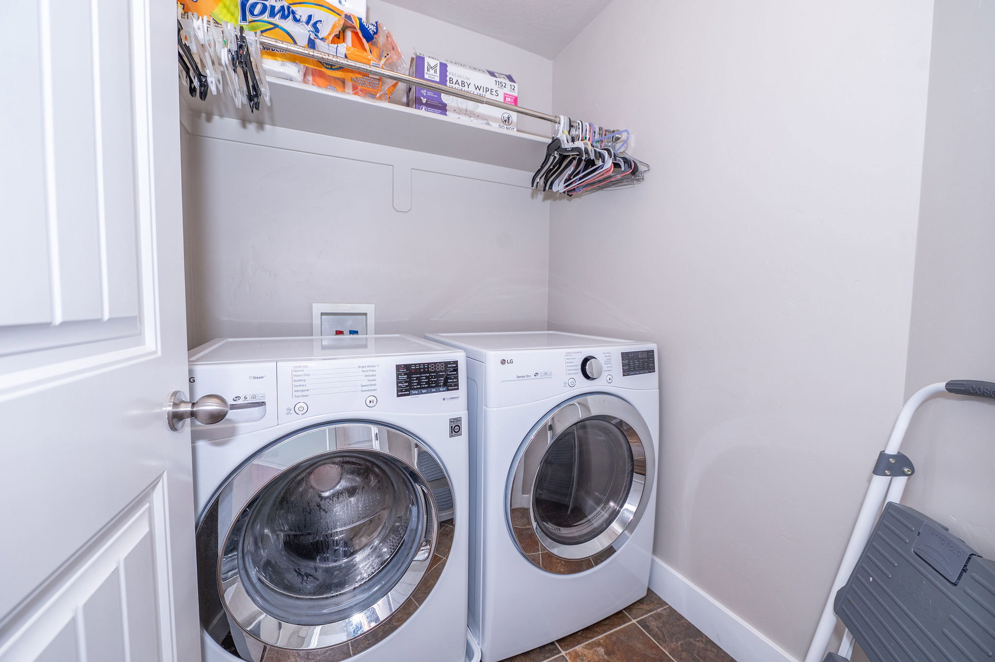 Dedicated laundry area featuring front-loading appliances, a built-in shelf, and a hanging rod
