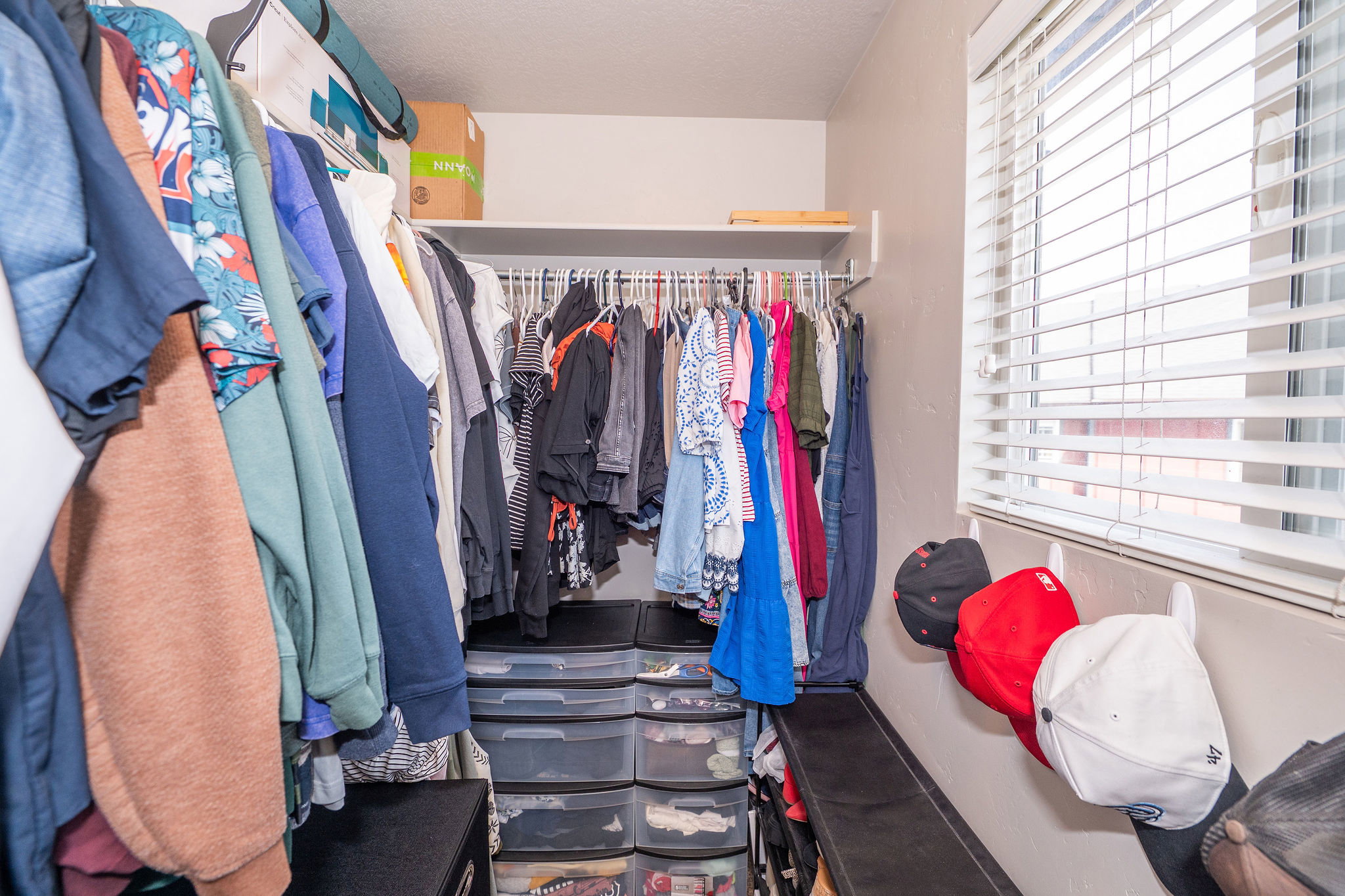Walk-in closet with integrated shelving, hanging rods, and a window with blinds