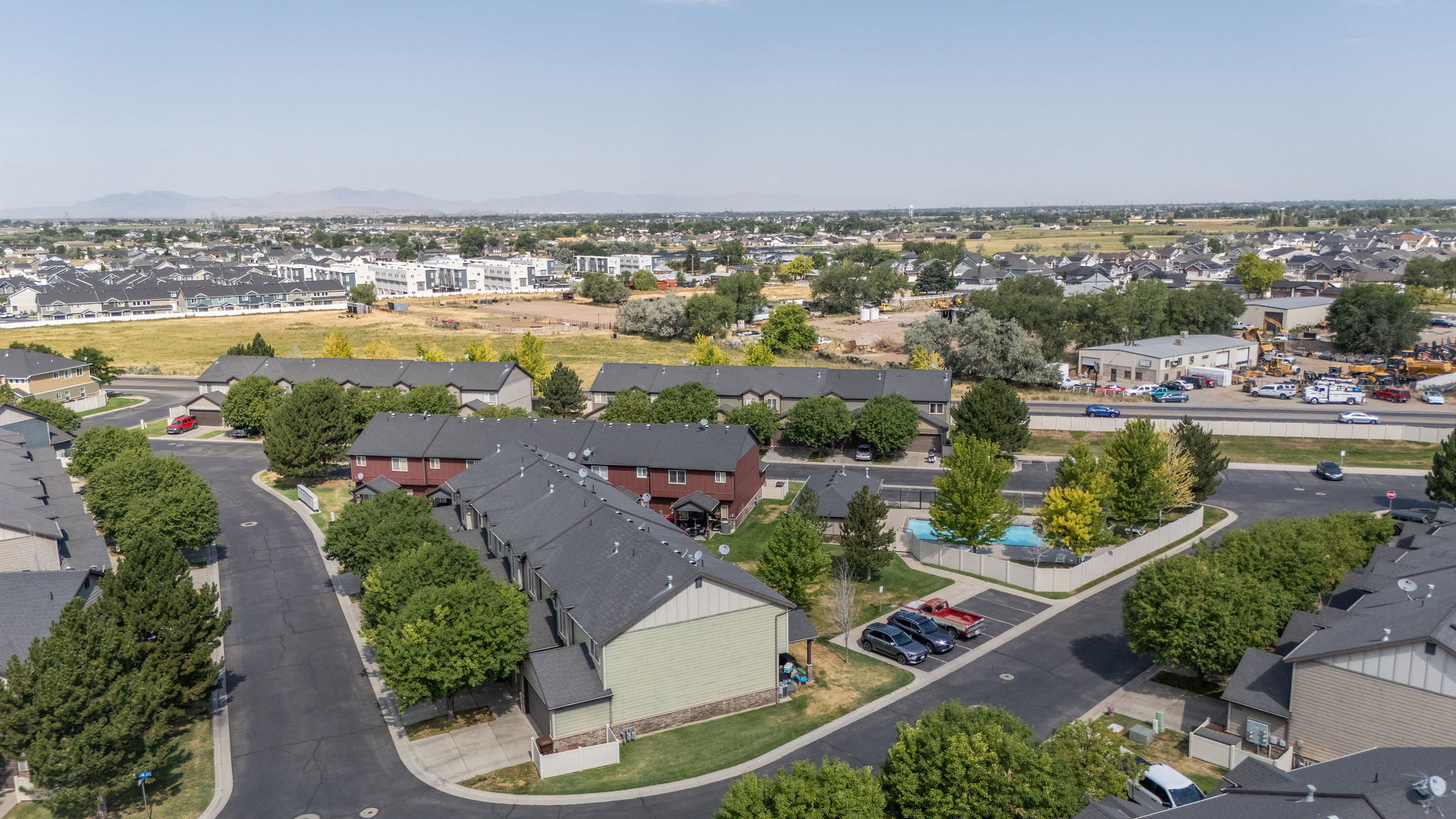 Aerial perspective featuring multiple residential structures with dark shingled roofs and mature trees