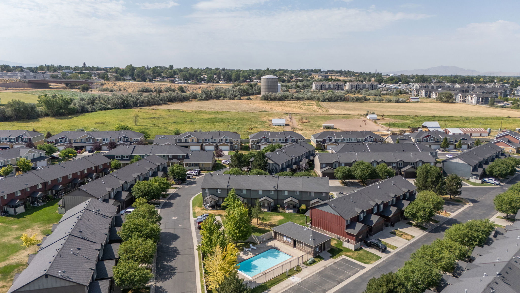 Residential community featuring townhomes with dark shingled roofs and light-colored siding