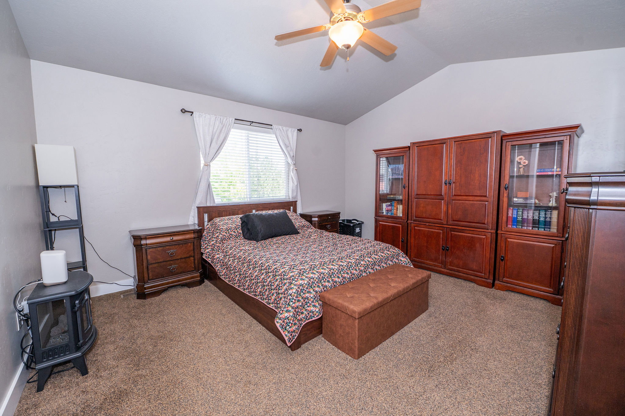 Carpeted room featuring a vaulted ceiling with a ceiling fan light fixture