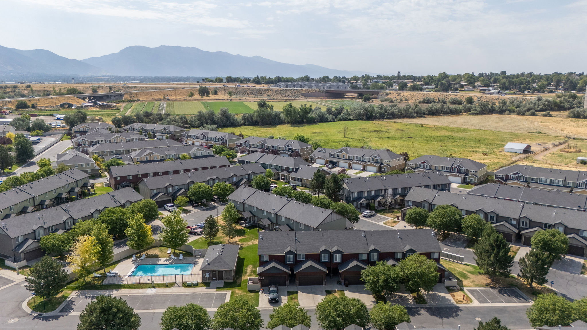 Aerial perspective of a multi-unit residential community featuring uniform townhome-style buildings with dark roofs
