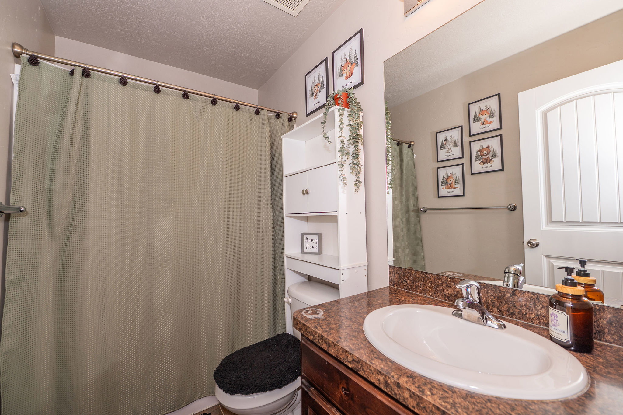 Bathroom vanity featuring an oval sink with a chrome faucet, a brown speckled countertop, and a large wall-mounted mirror