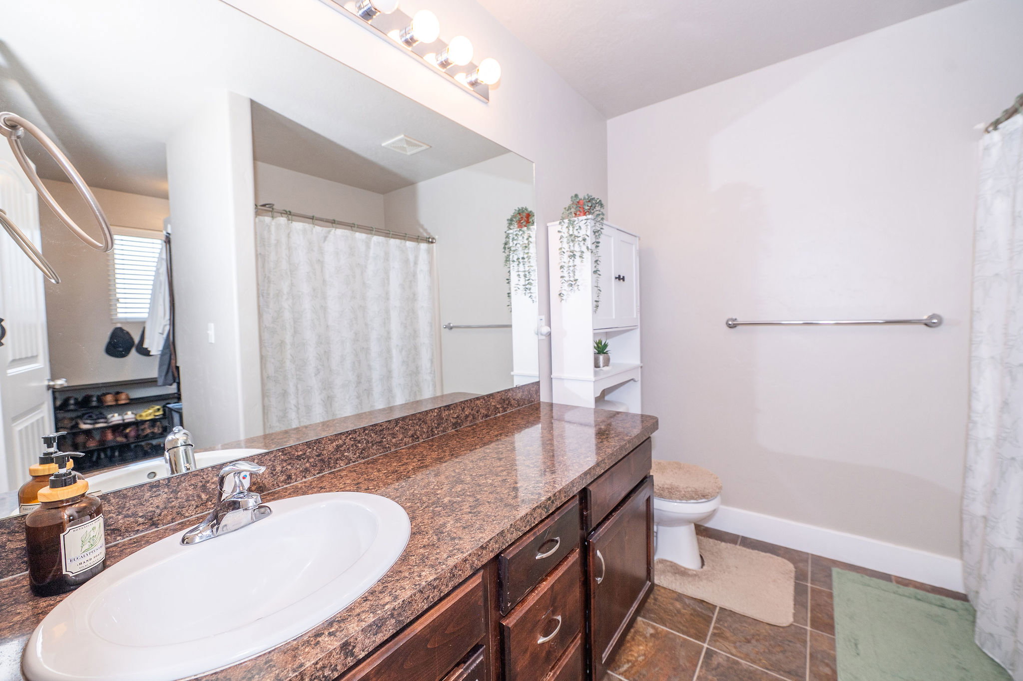 Bathroom featuring a vanity with dark wood-finish cabinetry, a white oval sink, and a speckled countertop