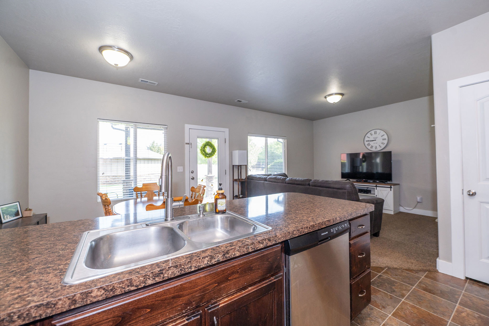 Kitchen island with a double basin stainless steel sink, pull-down faucet, and integrated dishwasher