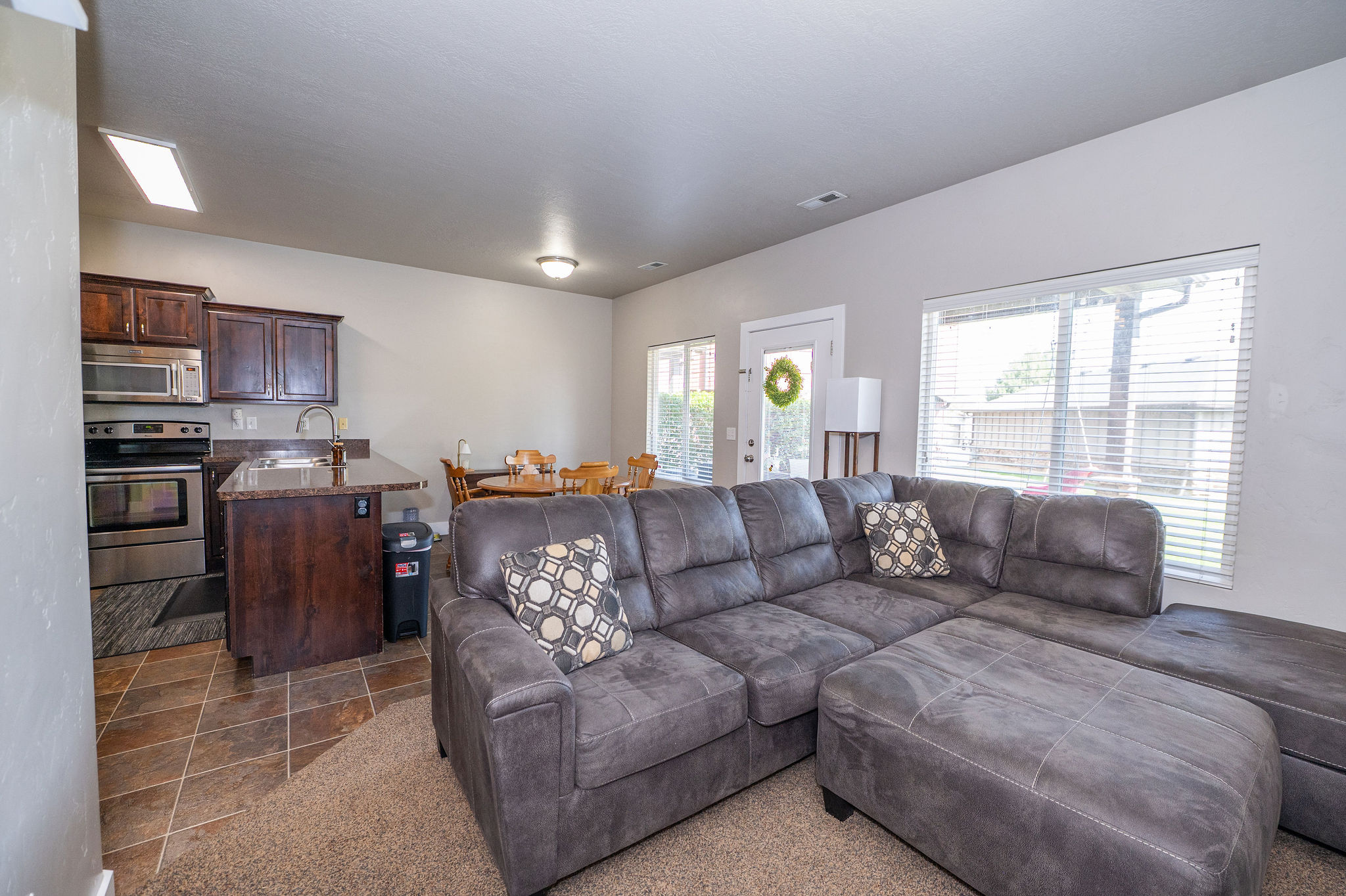 Open-concept living area featuring a kitchen with dark wood-finish cabinetry, stainless steel appliances, and a granite-style countertop