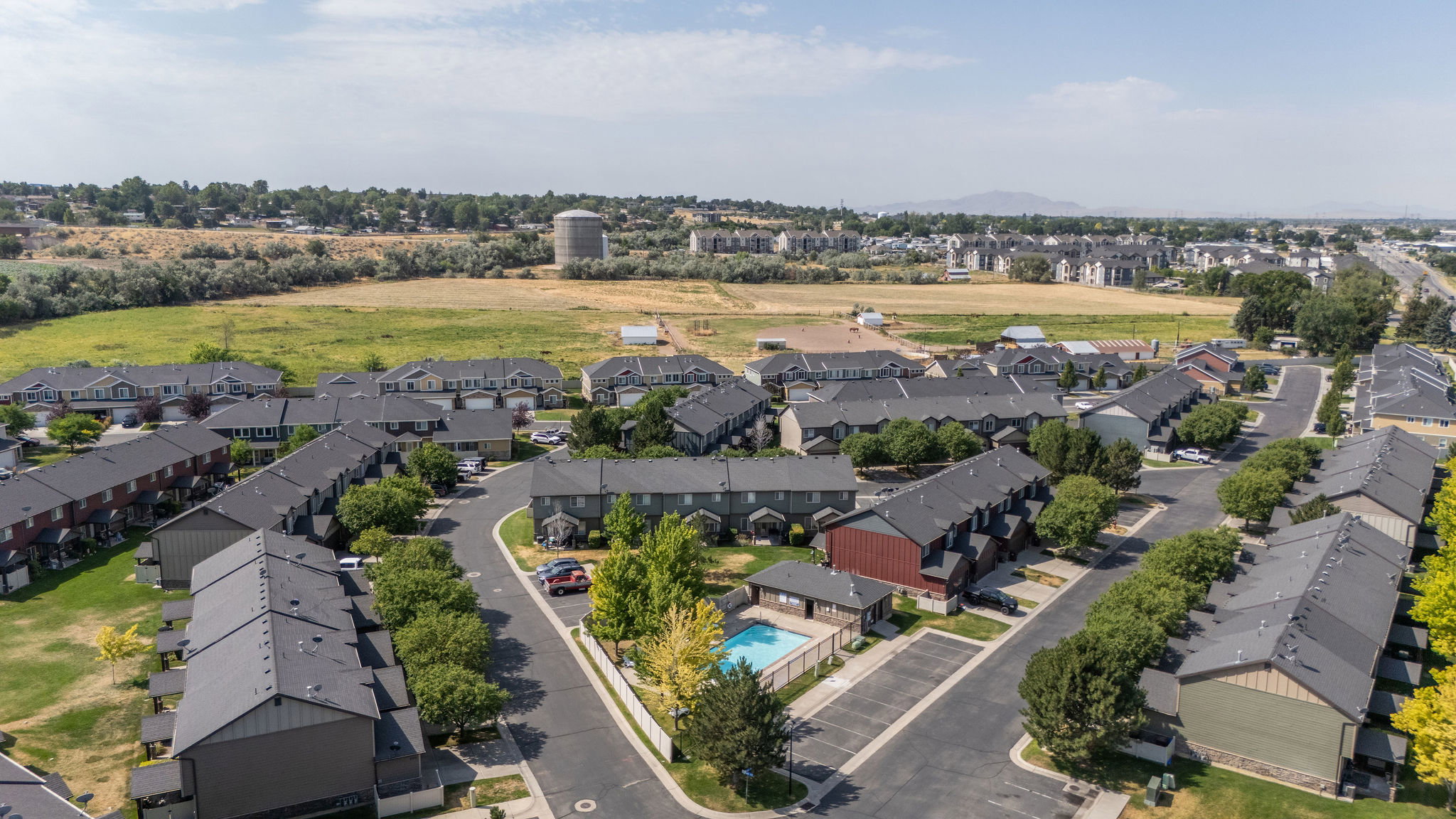 Aerial perspective of a multi-unit residential development featuring a central swimming pool and surrounding green spaces