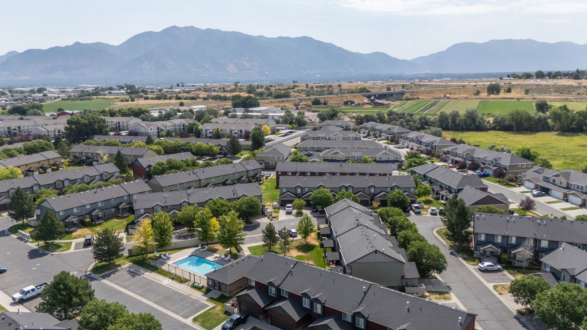 Aerial perspective showcasing a residential community with a central swimming pool and surrounding green spaces