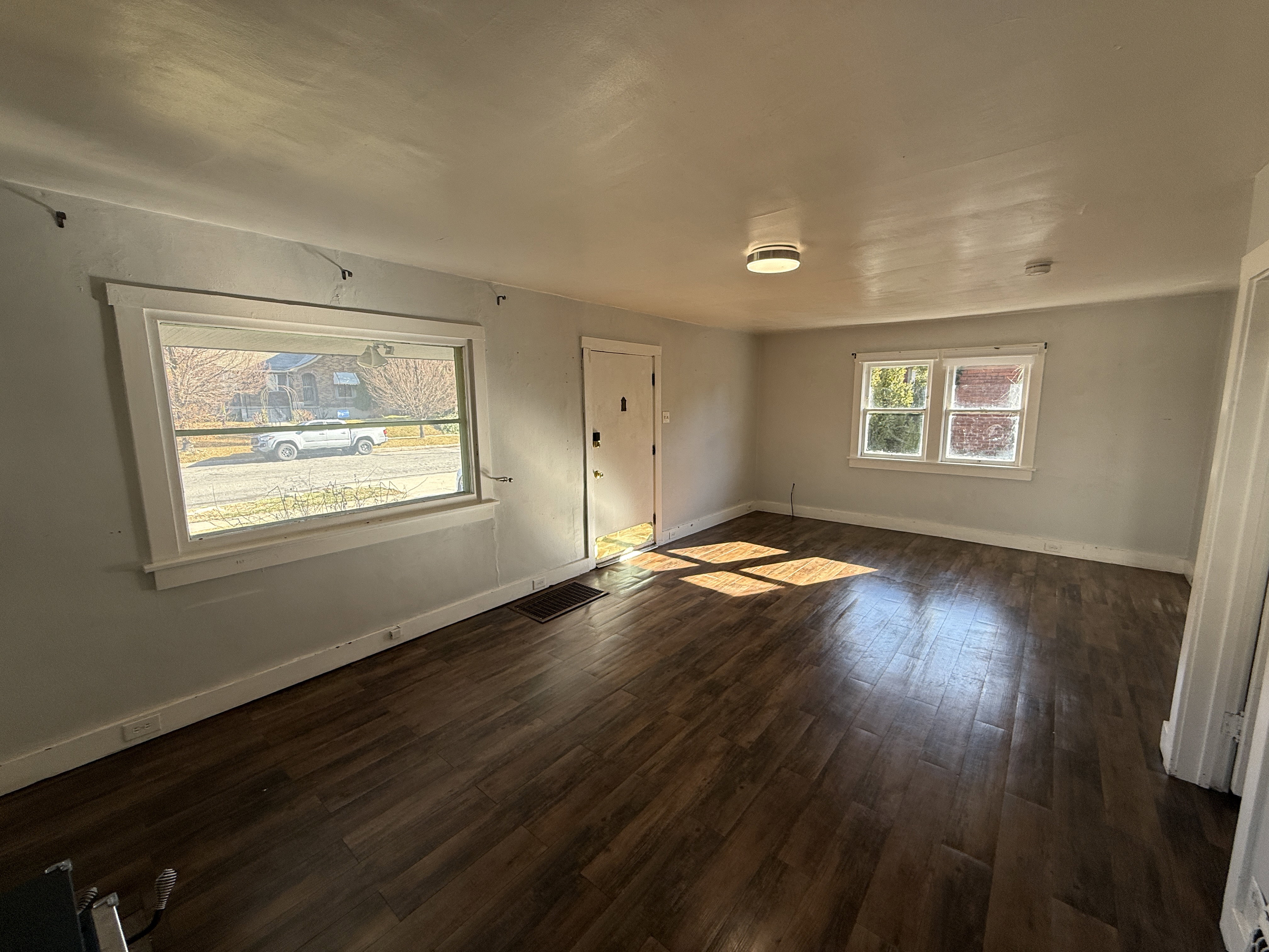 Spacious room featuring wood-finish flooring, light gray wall paint, and white trim