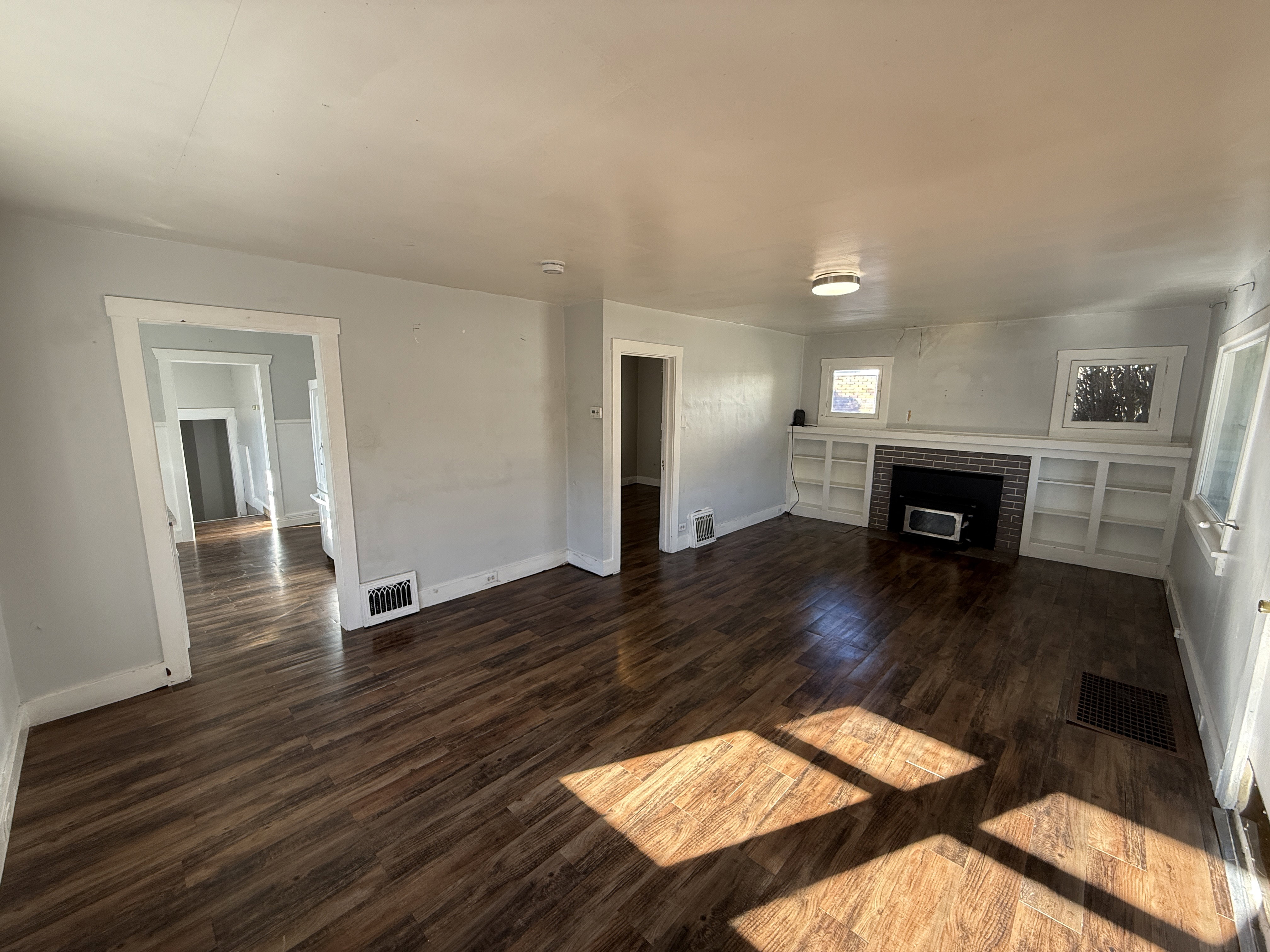 Living area featuring wood-finish flooring, a brick fireplace with a black insert, and built-in shelving