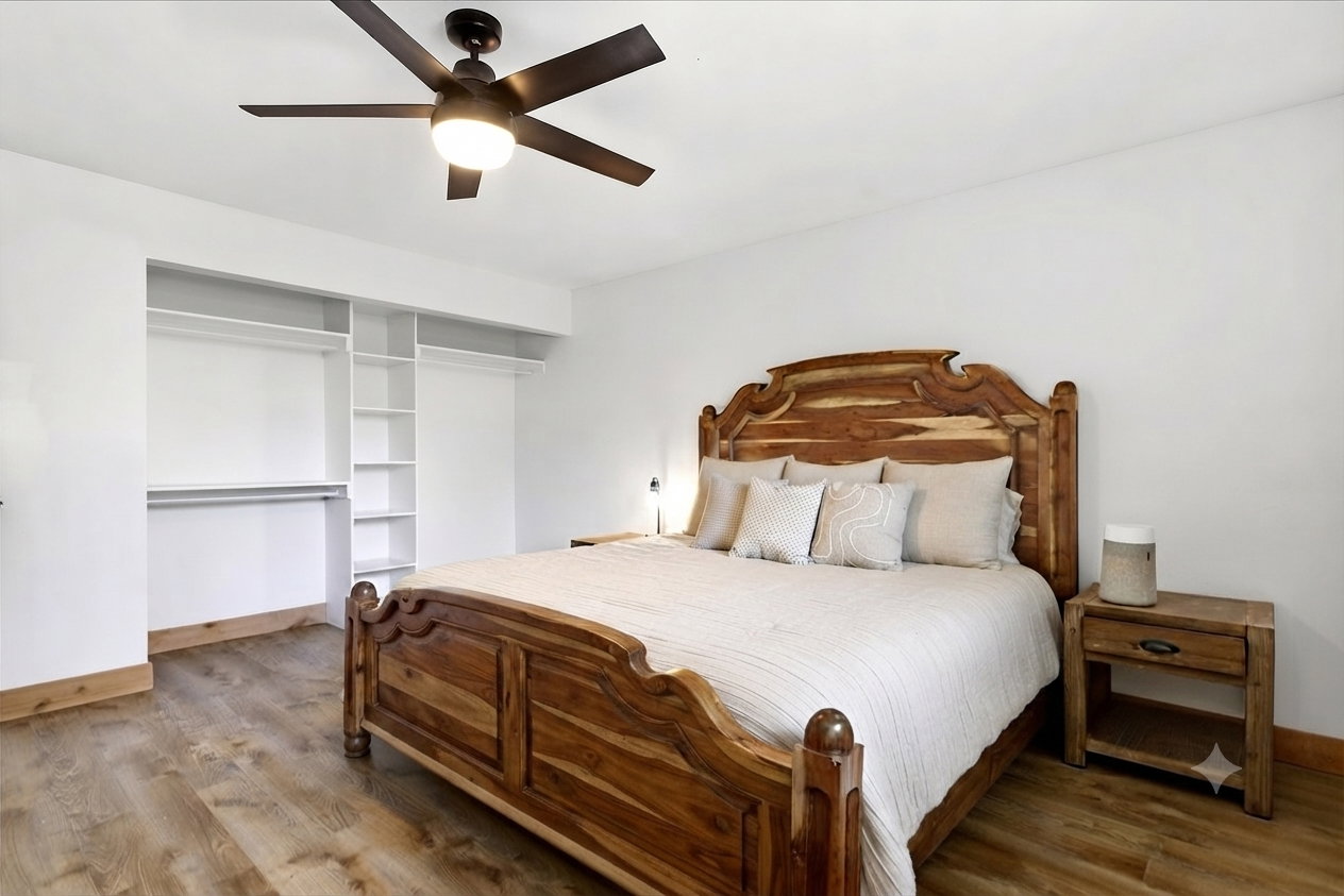 Bright room featuring wood-finish flooring, a ceiling fan with integrated lighting, white walls, and a built-in closet system with shelving and hanging rods