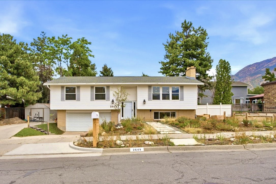 Split-level residence featuring white siding and gray shutters