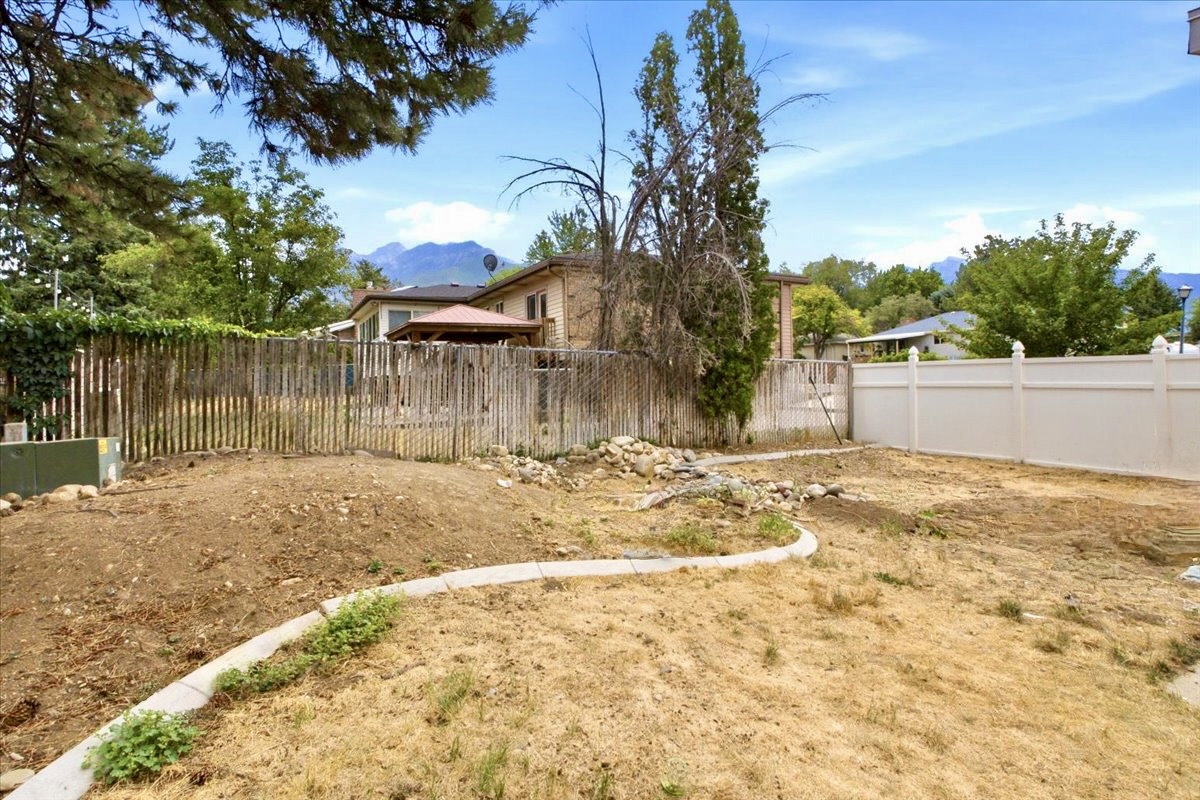 Expansive backyard space featuring a full fence and an installed planter border