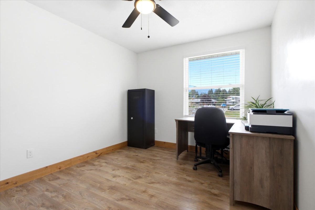 Bright room featuring wood-finish flooring, white walls, and a white-framed window with blinds