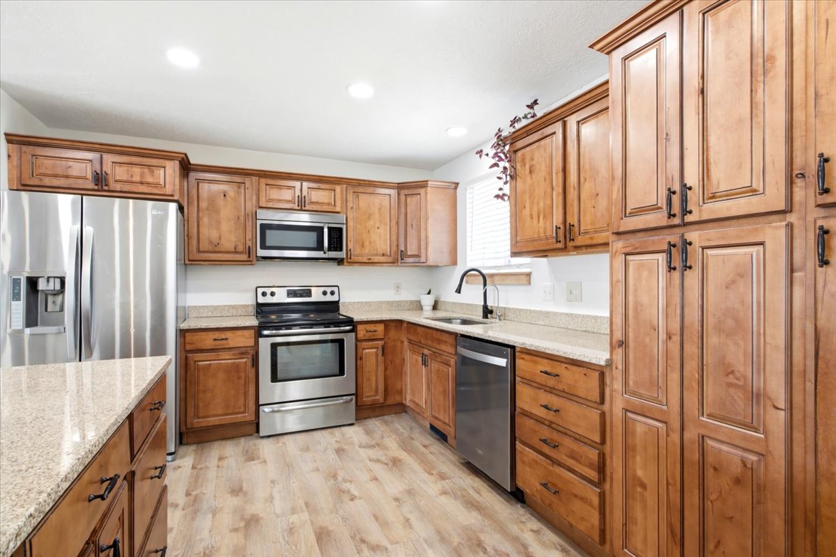Kitchen featuring wood-finish flooring, light-toned countertops, and a suite of stainless steel appliances