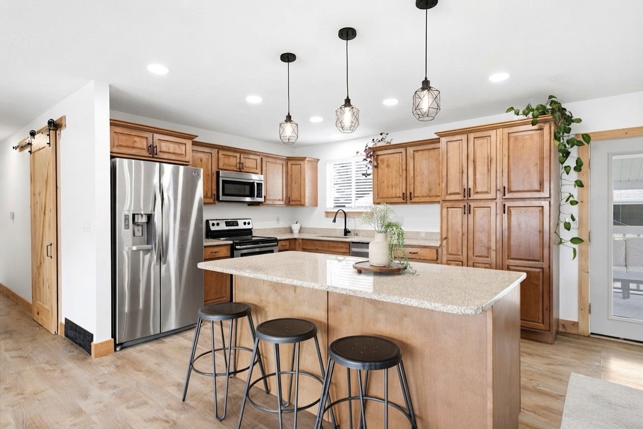 Well-appointed kitchen featuring light wood-finish cabinetry, stainless steel appliances, and a central island with a light-toned countertop