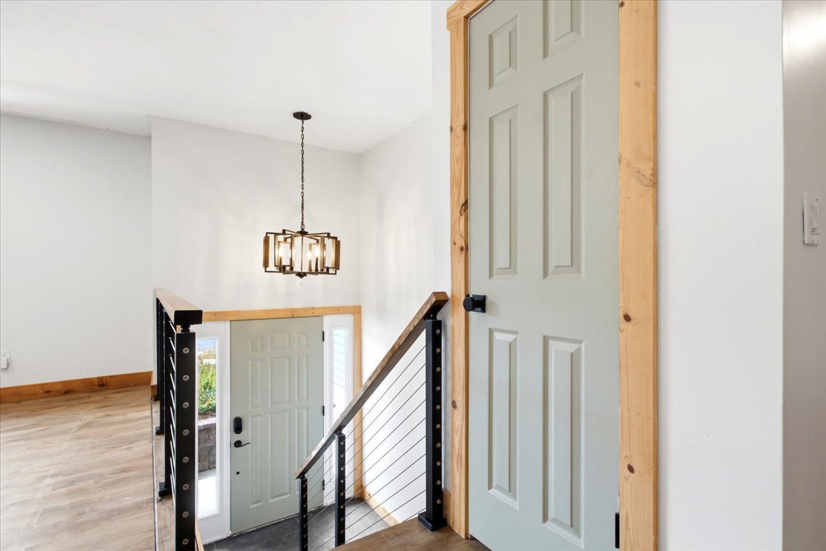 Foyer featuring a modern chandelier, wood-finish flooring, and a contemporary cable railing system